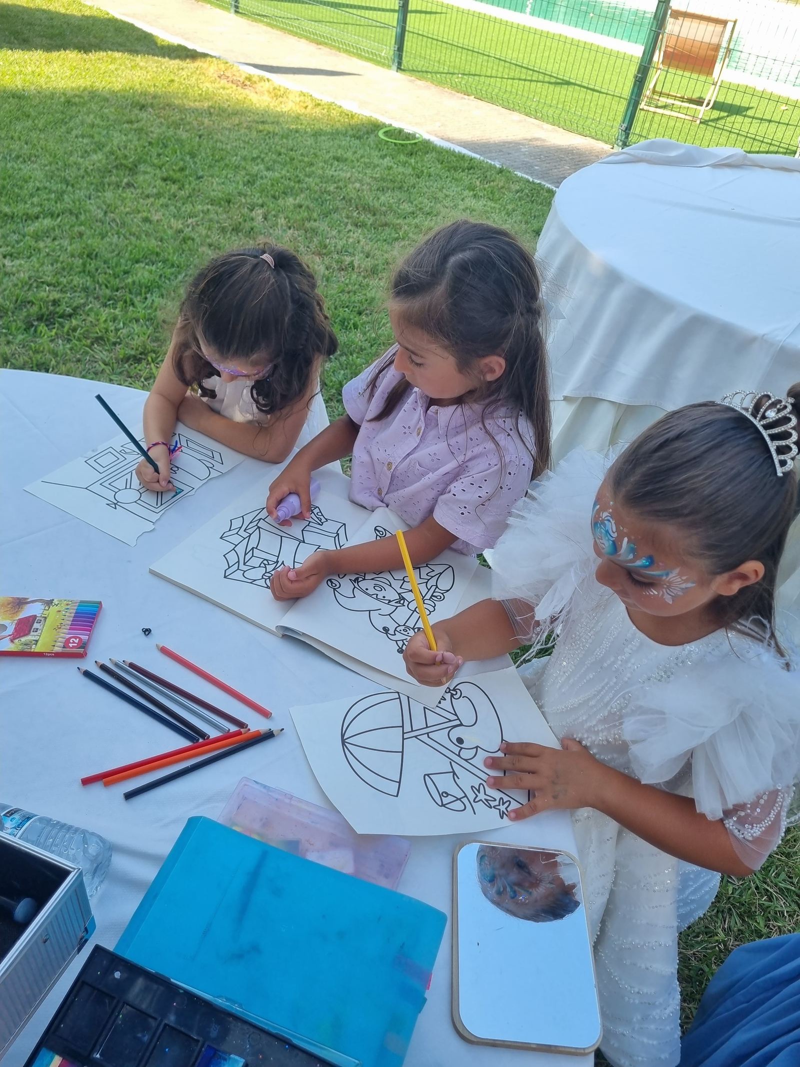 Crianças a pintar e a desenhar numa mesa de ateliê
