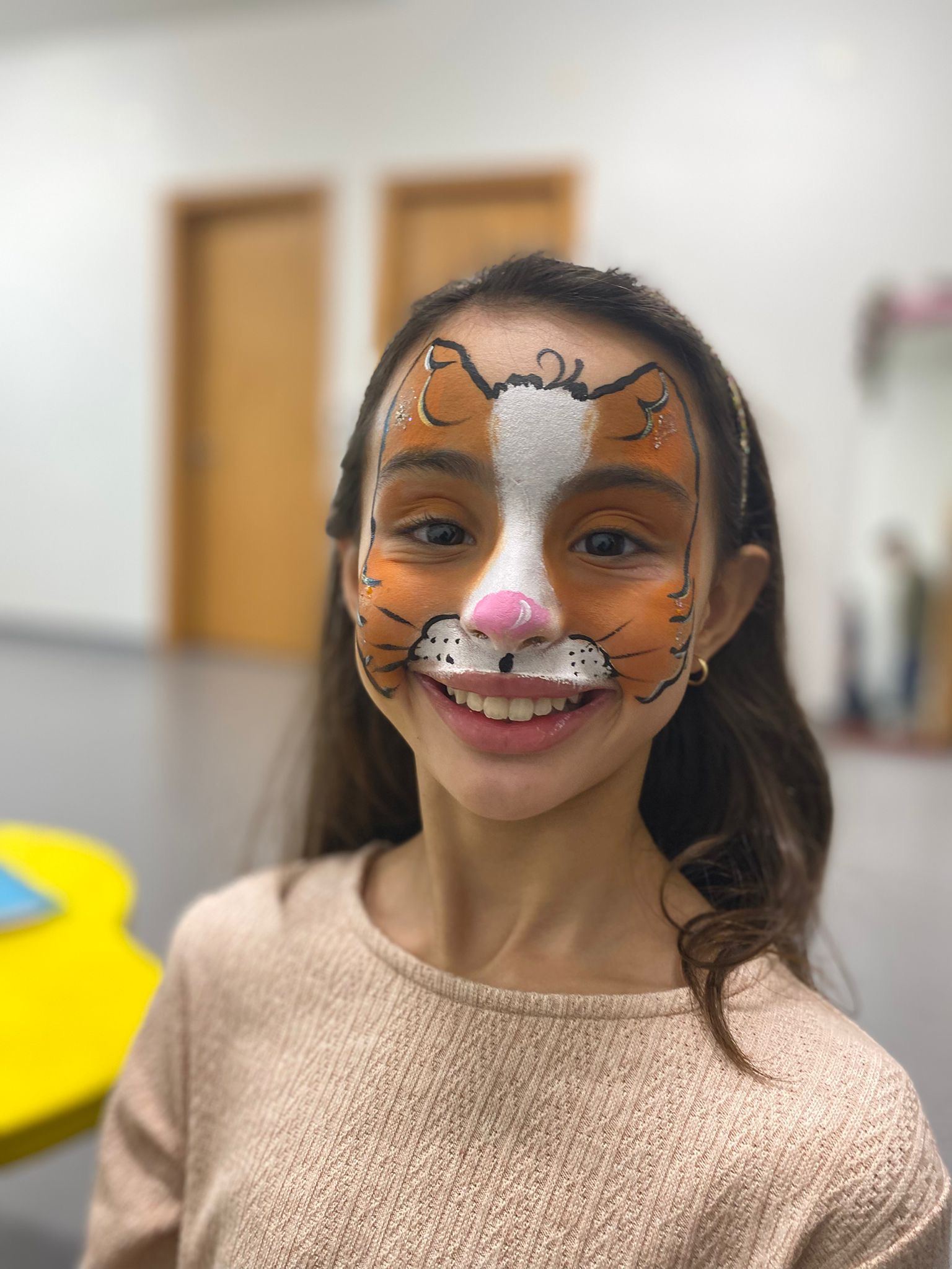 Criança com o rosto pintado de gato, a sorrir