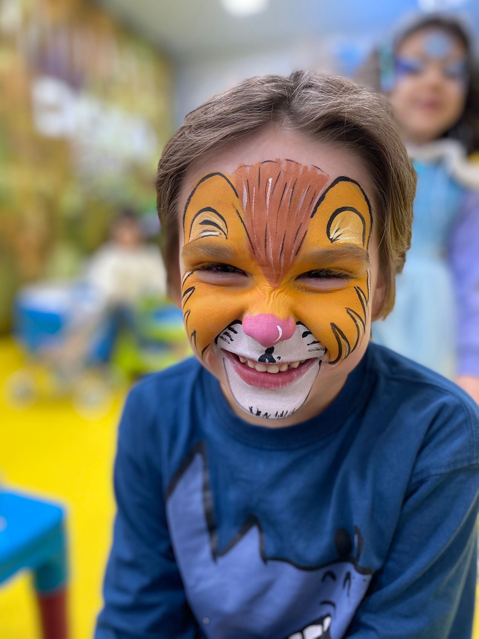 Criança com o rosto pintado de tigre, a sorrir